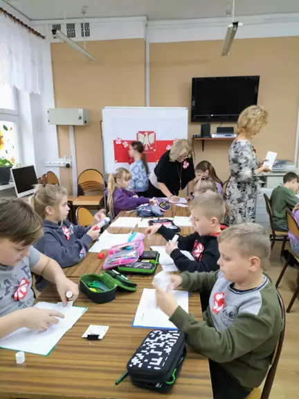 Uczniowie układają mapę Polski z puzzli.