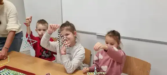 Grupa dzieci robi gwiazdki ze słomek 