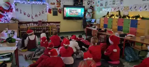 Dzieci z kl. IIIa siedzą na dywanie i oglądają świąteczną bajkę.