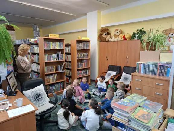 Dzieci z grupy 01 Biedronki siedzą na dywanie i słuchają informacji o książkach dla dzieci