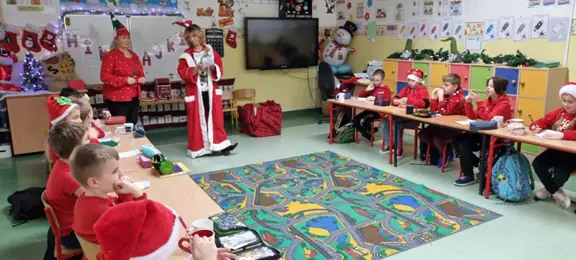 Panie bibliotekarki - pomocnice Mikołaja - rozdają dzieciom z kl. IIIa prezenty.