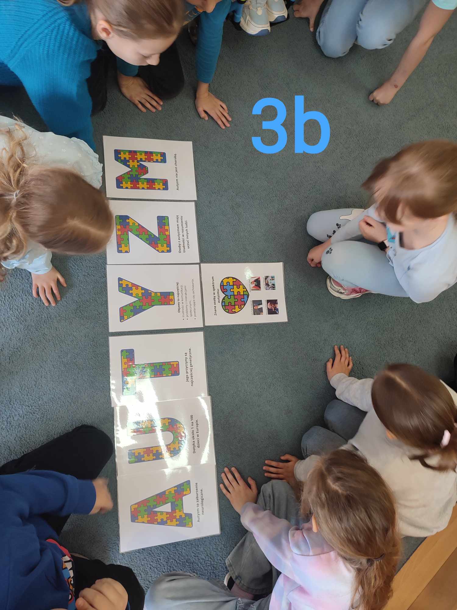 Uczniowie klasy trzeciej b czytają informacje o autyzmie