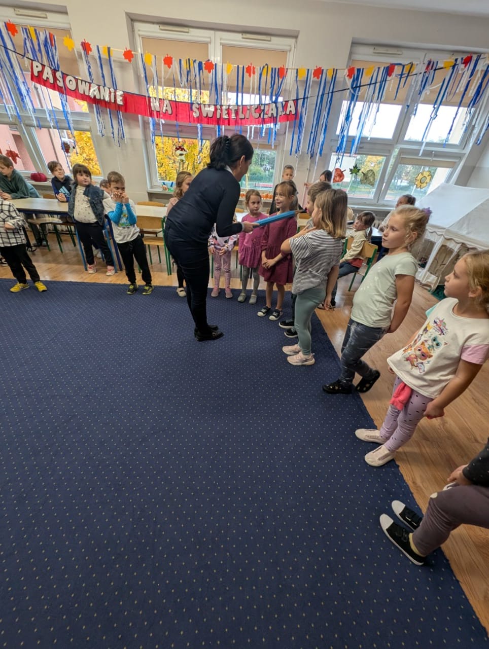 dyrektor szkoły przykłada ołówek do ramienia ucznia na znak pasowania