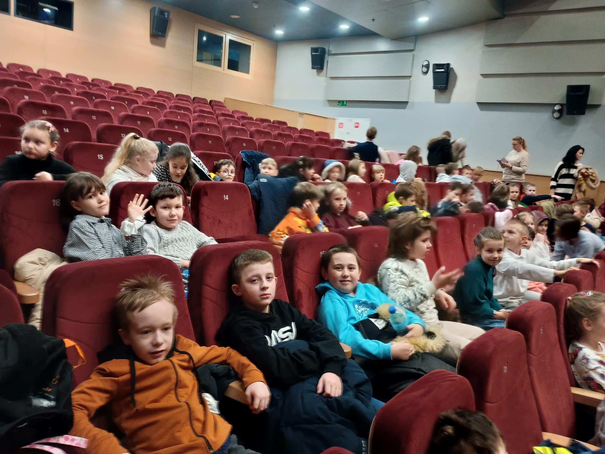 Uczniowie siedzący w kinie w oczekiwaniu na przedstawienie