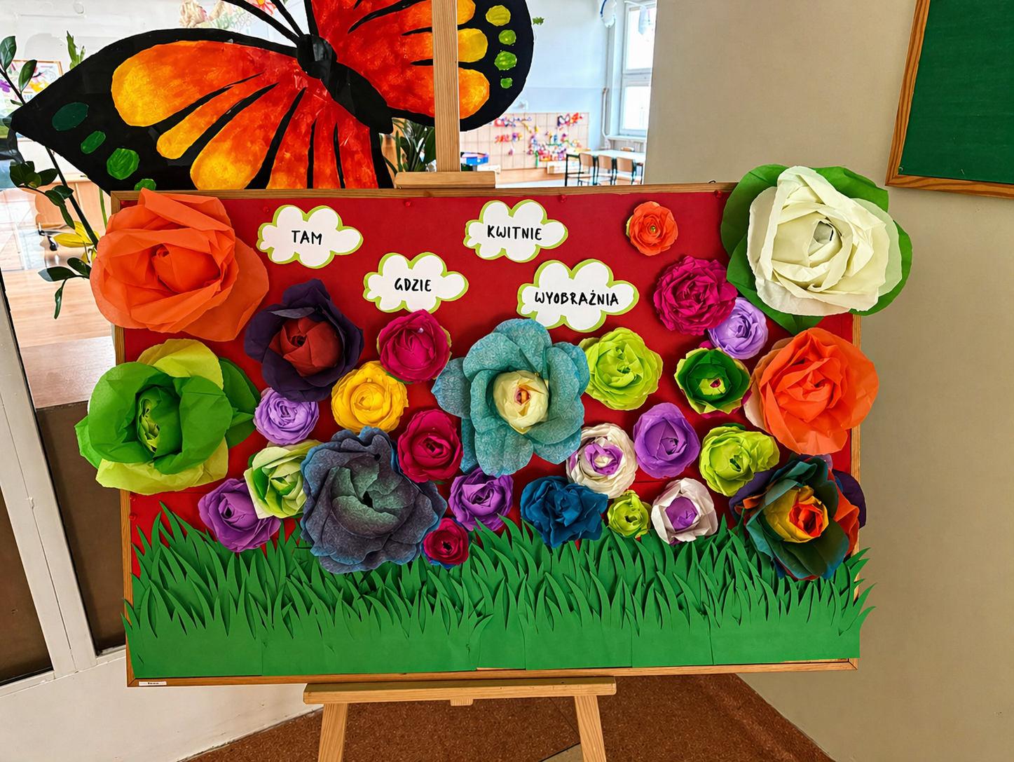 tablica na sztaludze z kwiatami z bibuły