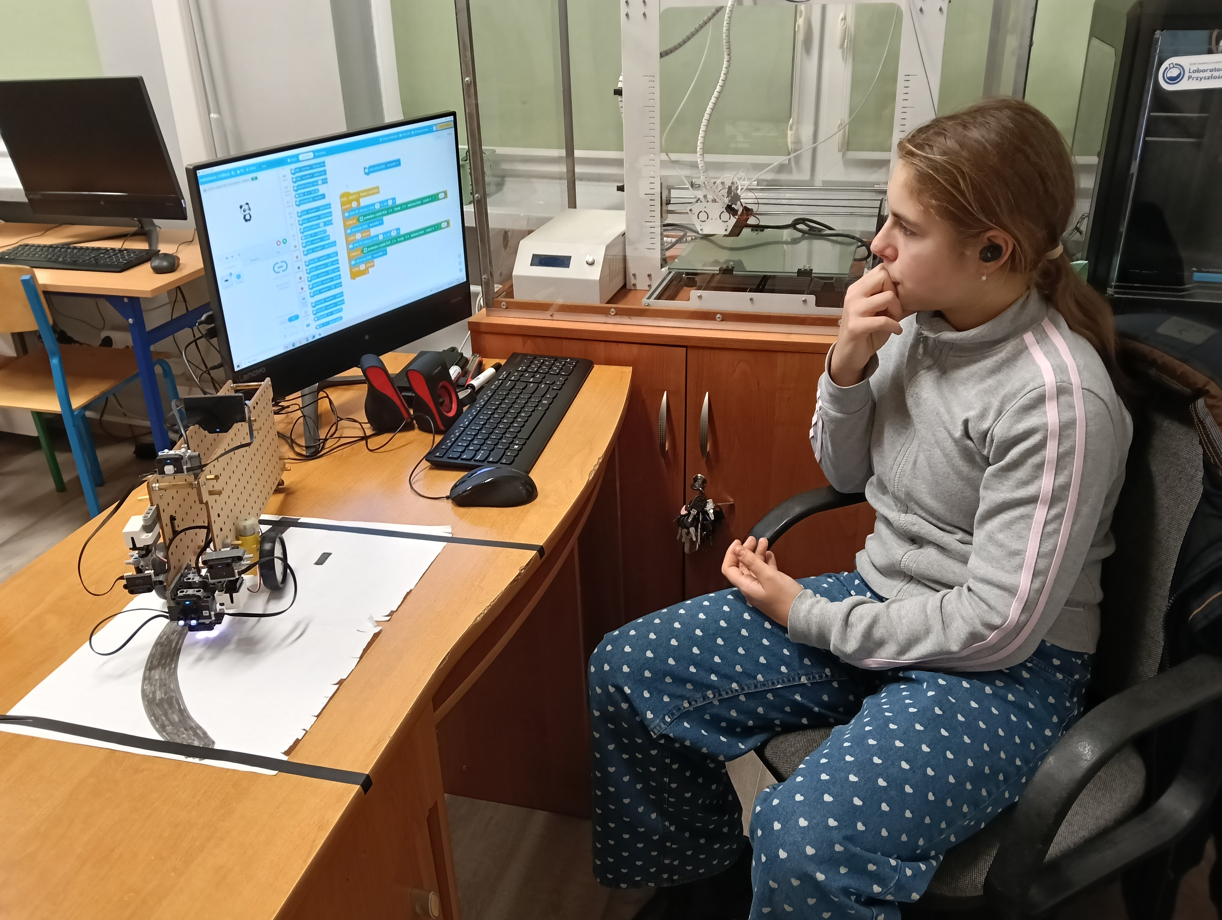 uczennica testuje program w mBlock dla robota kołowego CyberPi do jazdy wzdłuż linii